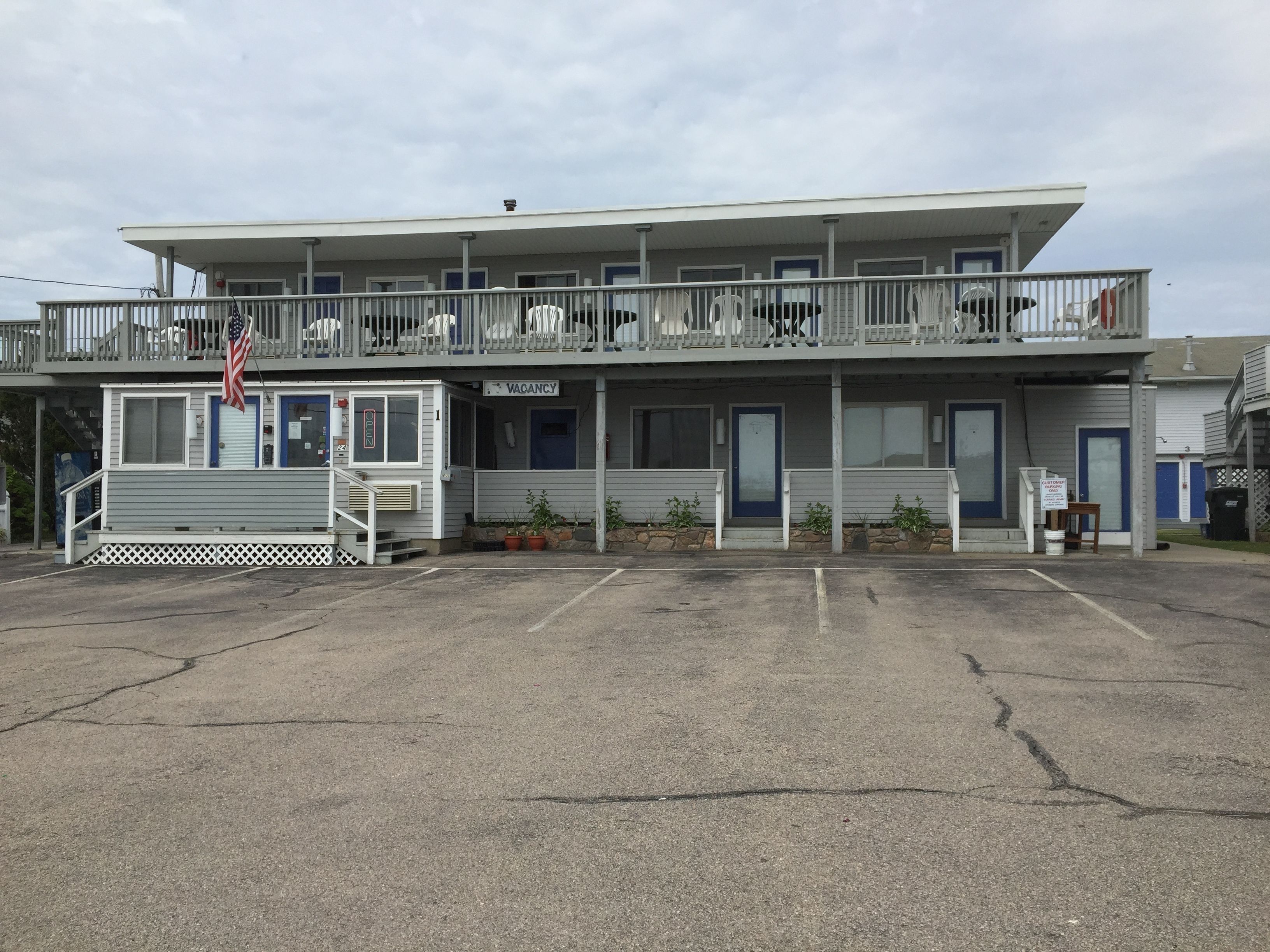 A motel with a two-story structure, a balcony on the upper floor, and a 'VACANCY' sign.