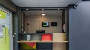 Zona de recepción con una pantalla digital, un televisor de pantalla plana y una cámara de seguridad.