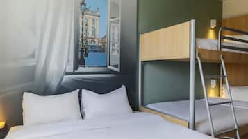 Une chambre d’hôtel avec un lit superposé, une grande fenêtre donnant sur un bâtiment historique et un rideau partiellement tiré sur le côté.