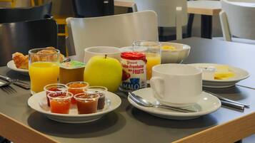 Ein Frühstückstisch mit Croissants, Obst, Saft und einer Schüssel Müsli.
