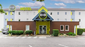 Un hotel B&B de diseño moderno, con un logo destacado, fachada azul y amarilla y entrada con portón.