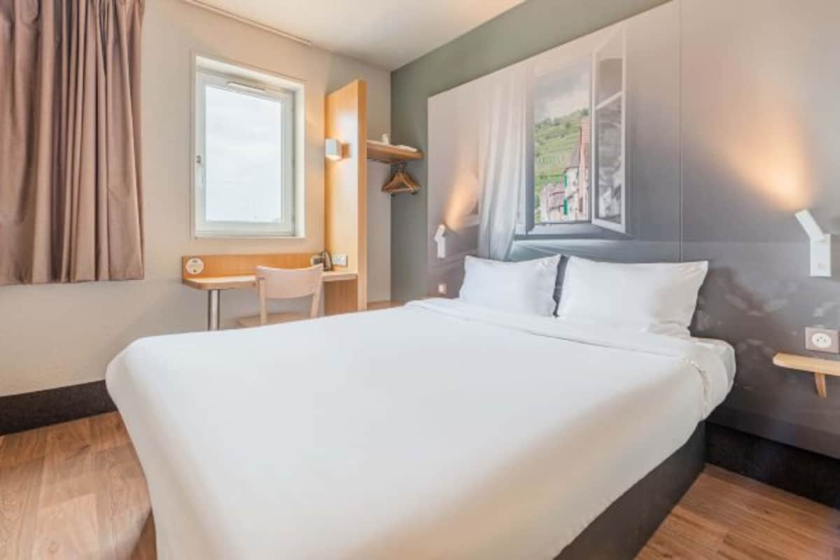 Una habitación de hotel moderna con una cama grande, un escritorio y una silla.