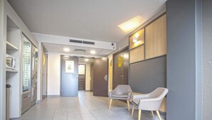 A modern hallway with a tiled floor, a vending machine, and two chairs against a wall. - B&B HOTEL Mulhouse Ile Napoléon (Illzach)