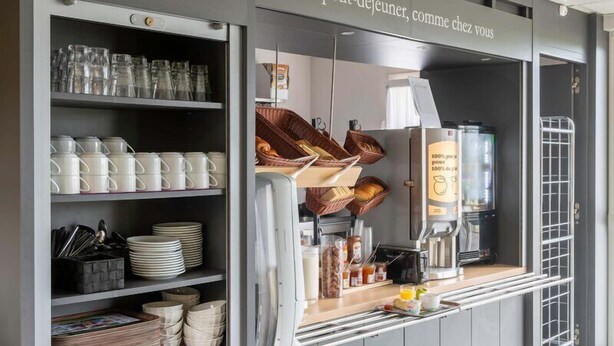 A kitchenette with shelves of dishes, a coffee machine, and baskets.