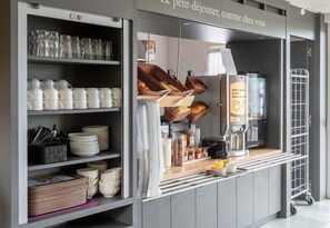 Une petite cuisine équipée d’étagères remplies de vaisselle, d’une machine à café et de paniers.