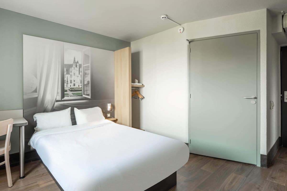 Una habitación de hotel moderna con una cama grande, un escritorio y un armario.