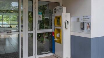 A building entrance with a glass door, a yellow vending machine, and a sign indicating a need for help.