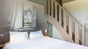 A bedroom with a bed, a nightstand, a wall-mounted lamp, and a staircase.