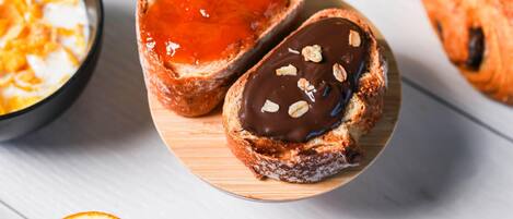 Two pastries on a wooden board, one with a red filling and the other with chocolate and nuts.
