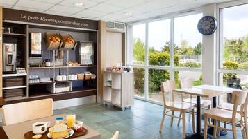 A modern cafe with a breakfast setup, including a tray with toast, juice, and yogurt.