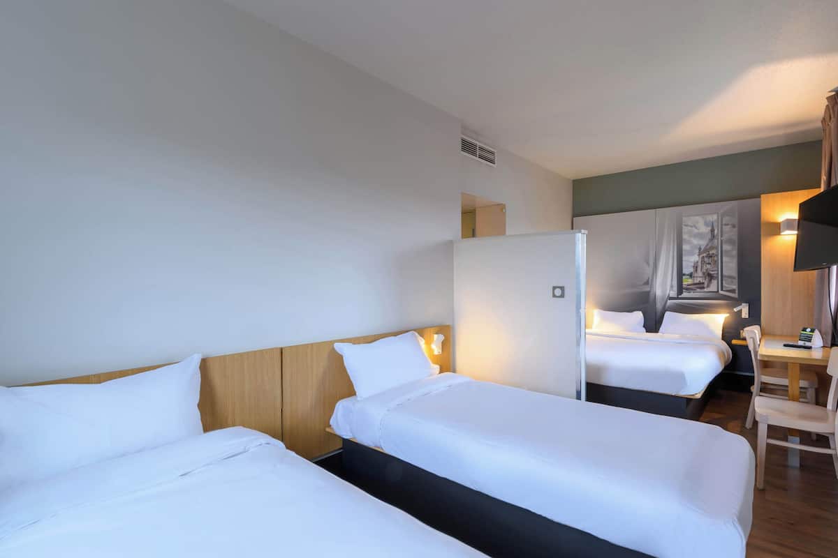 Een hotelkamer met twee enkele bedden, een bureau en een stoel.