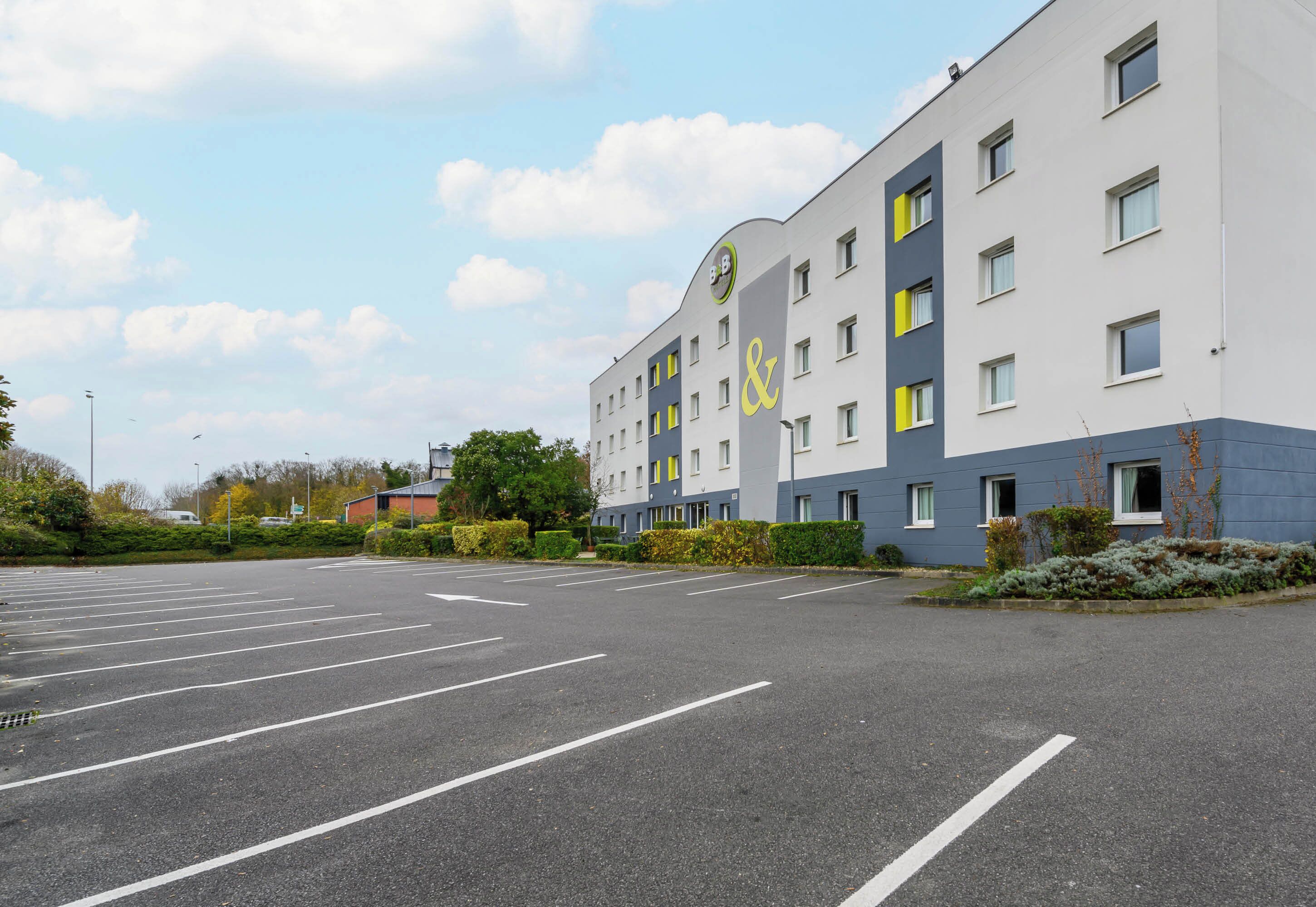 Un hôtel à plusieurs étages avec un parking situé devant.