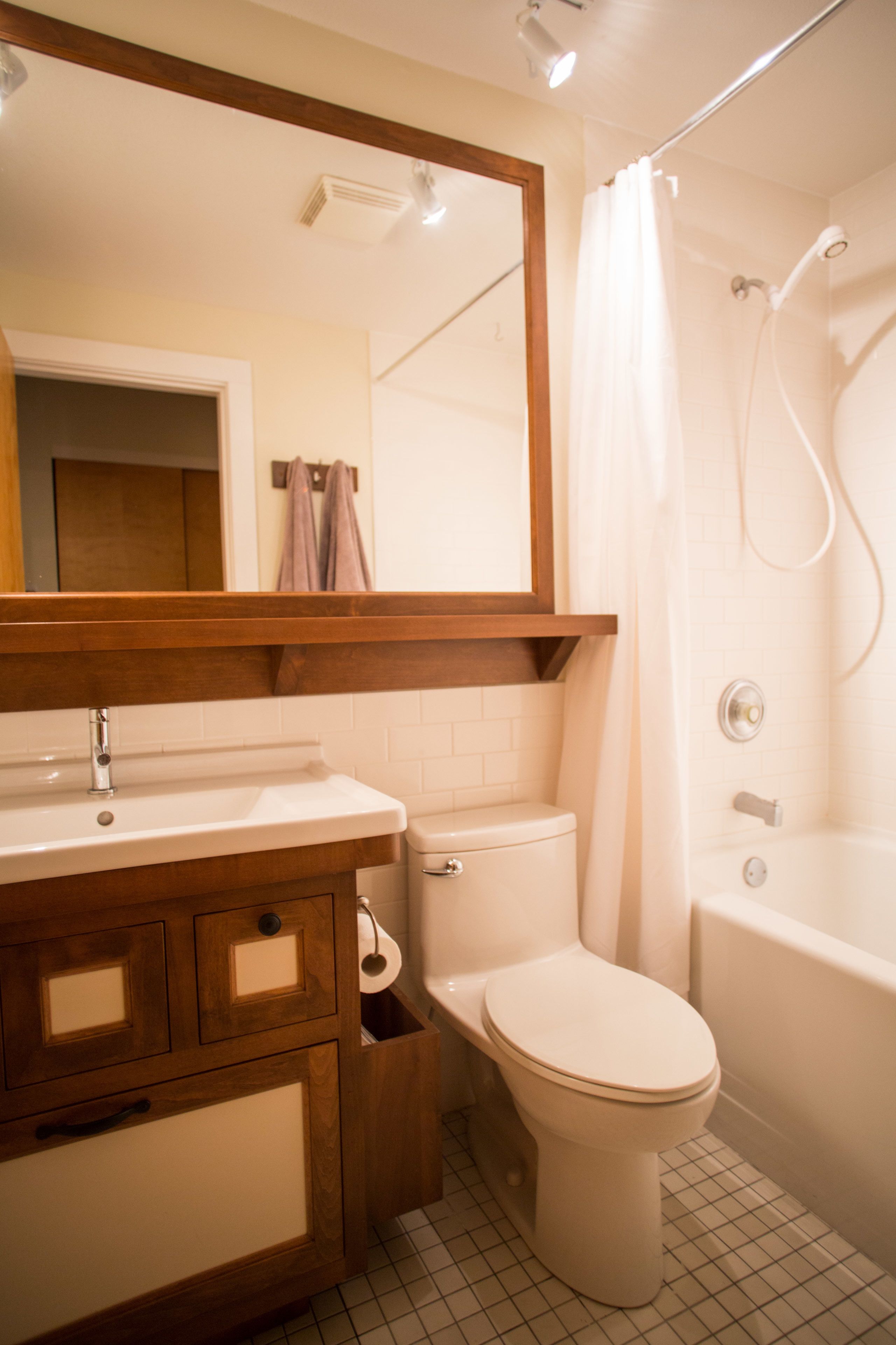 A bathroom with a wooden vanity, a toilet, a bathtub, and a shower.