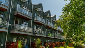 Un immeuble résidentiel moderne à plusieurs étages, doté de balcons, de grandes fenêtres et d’un jardin bien entretenu.