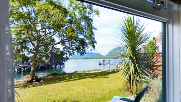 Une vue d’un lac avec un quai, un arbre et une chaise au premier plan.