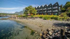 Un hôtel situé sur la côte, doté de nombreux balcons, bordé d’une plage rocheuse et offrant une vue dégagée sur la mer.