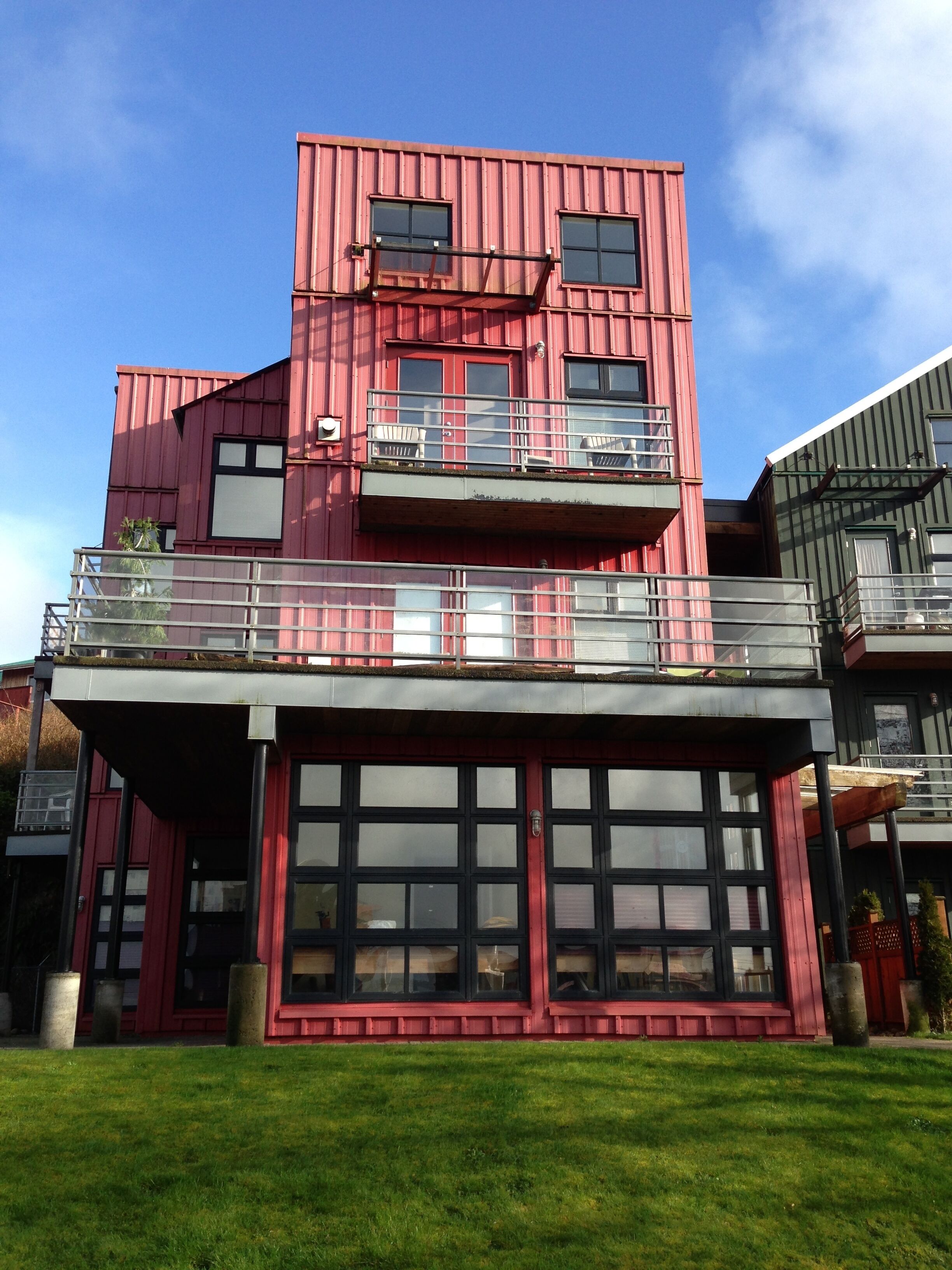 En bygning med flere etager, rød facade, balkon på anden sal og indkørsel til garage.