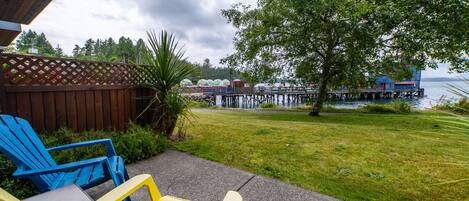 A patio with outdoor seating, a wooden deck, and a view of a dock and water.