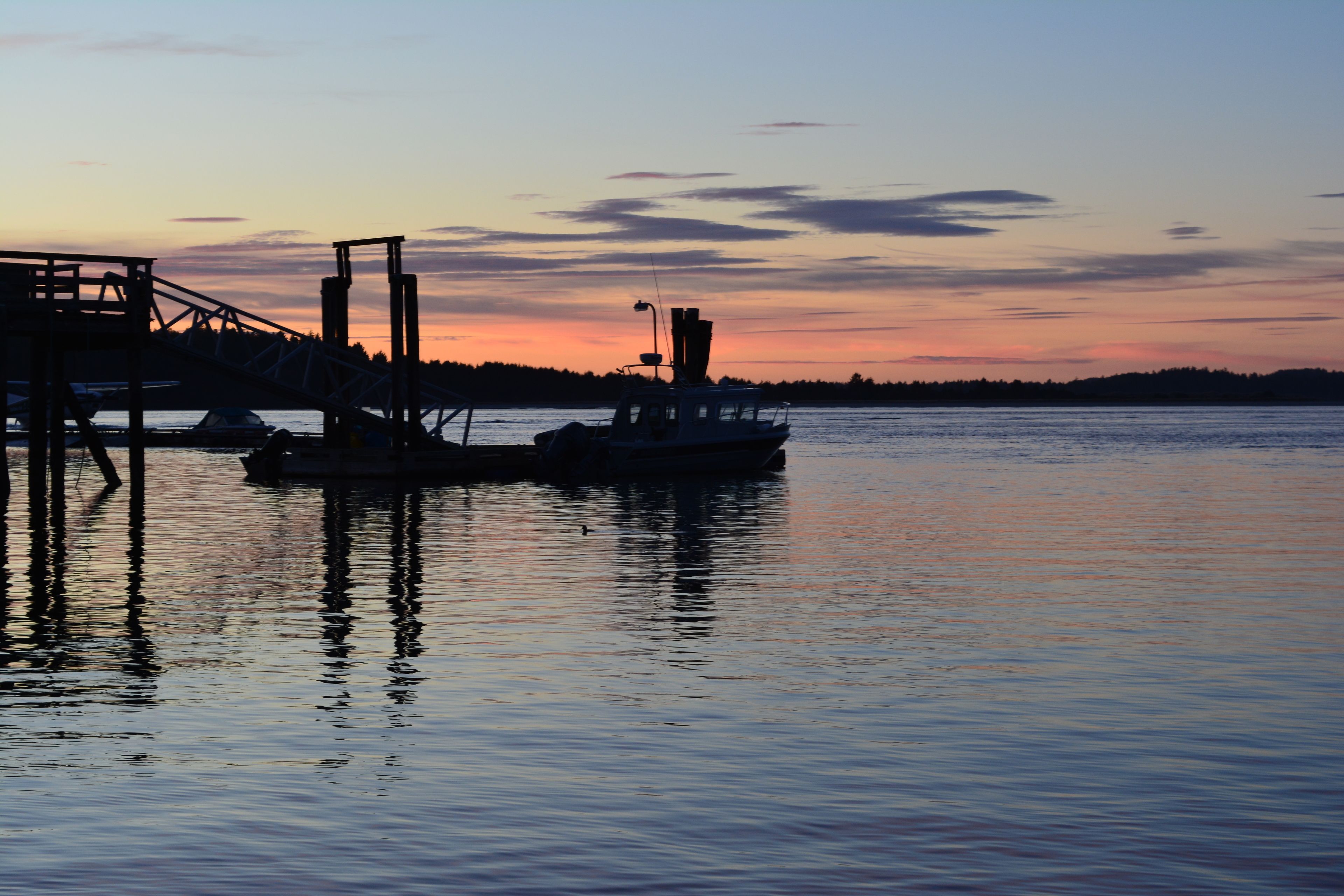 A dock with a boat and a pier structure during sunset.