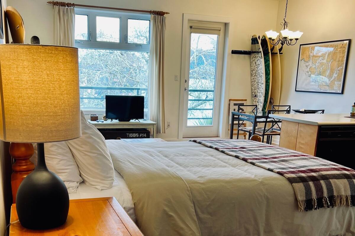 A bedroom with a bed, a TV, a desk, and a chair.