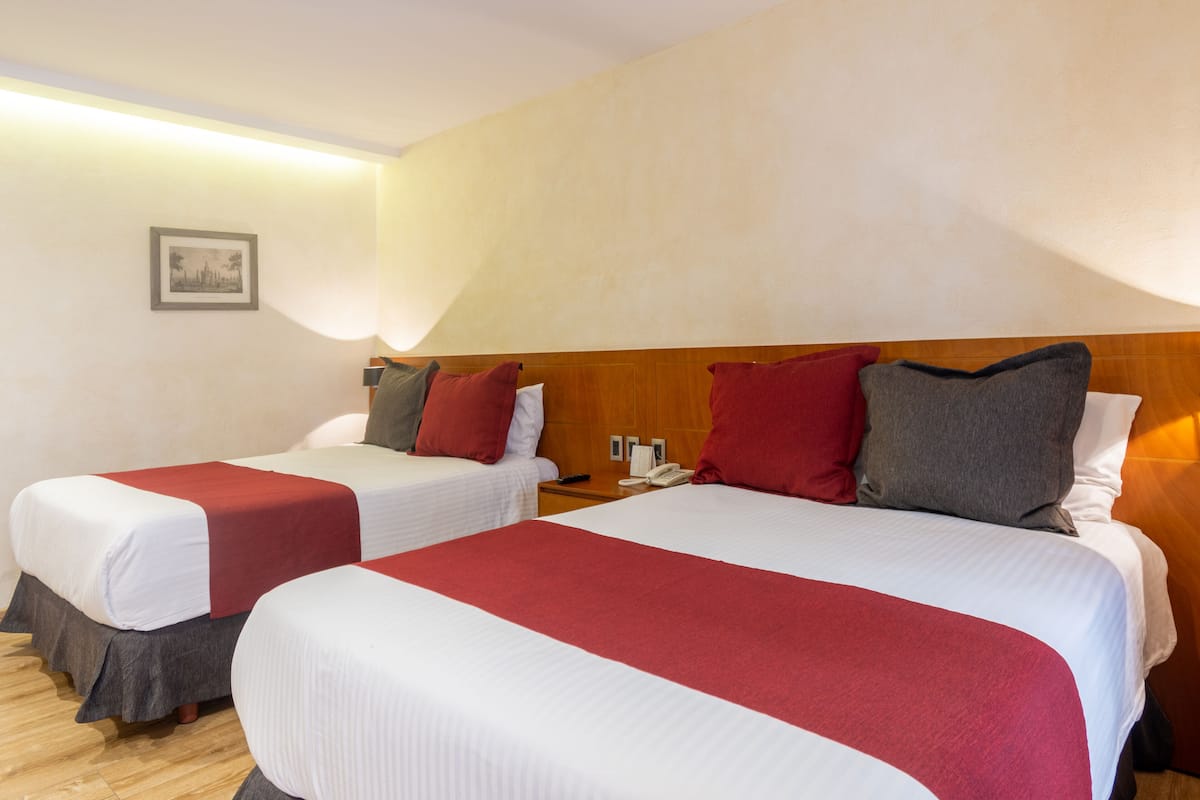 Two single beds with red and white bedding, wooden headboards, and a bedside table with a phone.
