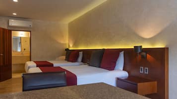 A hotel room with two beds, a wooden headboard, a granite countertop, and a wall-mounted air conditioner.