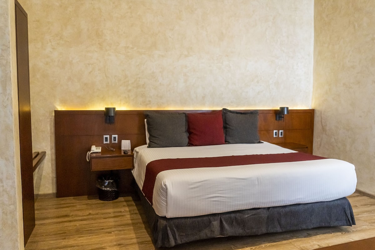 A neatly made bed with a white and red bedspread, a wooden headboard, and two bedside lamps.