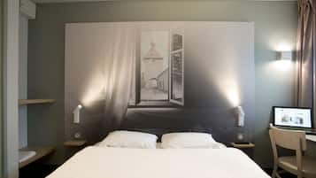 Ein Hotelzimmer mit Bett, Nachttischlampen, einem Schreibtisch mit Laptop und einem großen Fenster mit Blick auf ein Gebäude.
