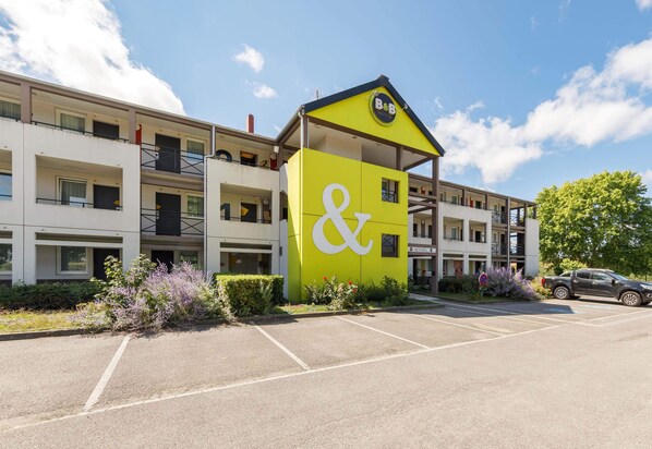 Un edificio de varios pisos con un llamativo letrero amarillo y blanco que muestra el símbolo “&” y “B&B”.