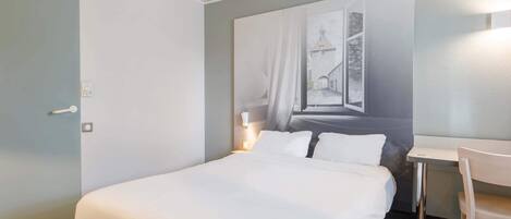 Una habitación de hotel con una cama grande, un escritorio y una silla.