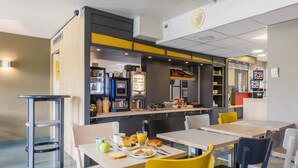 A modern cafe with tables and chairs, a coffee machine, and a menu board. - B&B HOTEL Moulins Toulon‑sur‑Allier (Toulon-sur-Allier)