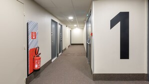 Un pasillo con puertas, un extintor y un gran número 1 en la pared.