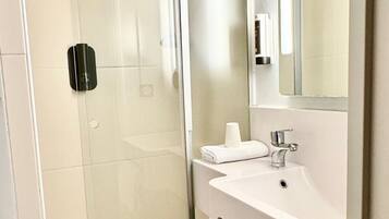A modern bathroom with a glass shower enclosure, a white sink, and a mirror above the sink.