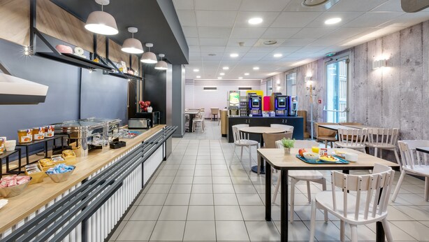Una cafetería moderna con una barra alargada, varias zonas de estar y una amplia variedad de comida y bebidas.