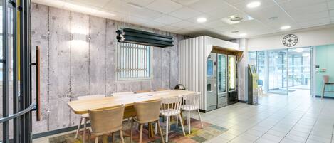 A modern meeting room with a long table, chairs, a patterned rug, and a clock on the wall.