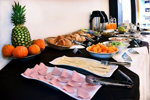 Buffet com diversas opções de comida, incluindo frutas, doces e carnes.