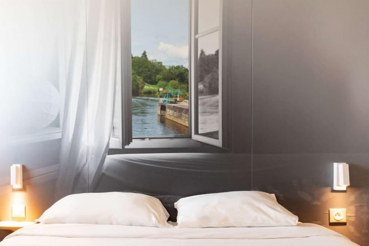 A bedroom with a large window, a bed, and two wall-mounted lights.