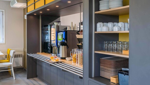 A modern kitchen area with a coffee machine, a microwave, and a variety of utensils and containers.