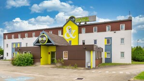A B&B hotel with a distinctive yellow and brown facade, multiple windows, and a clear blue sky in the background.