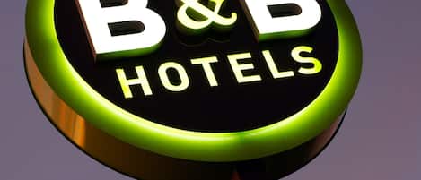 Una señal circular con el texto "B&B HOTELS" sobre un cielo morado.