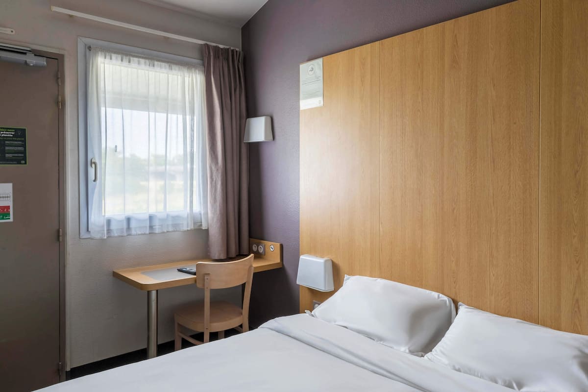 Une chambre d’hôtel avec un lit, un bureau et une chaise.