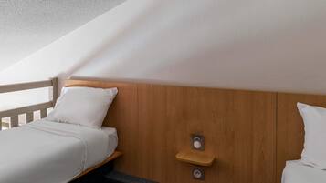 Une chambre avec deux lits, des têtes de lit en bois, une petite étagère en bois et un plafond à texture.