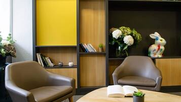 Una habitación con dos sillones de cuero, una mesa de madera con un libro abierto y una estantería con libros y objetos decorativos.