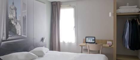 A hotel room with a bed, a desk, and a wardrobe.