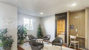 Een receptie met zitplaatsen, een houten receptiebalie en een groot raam.