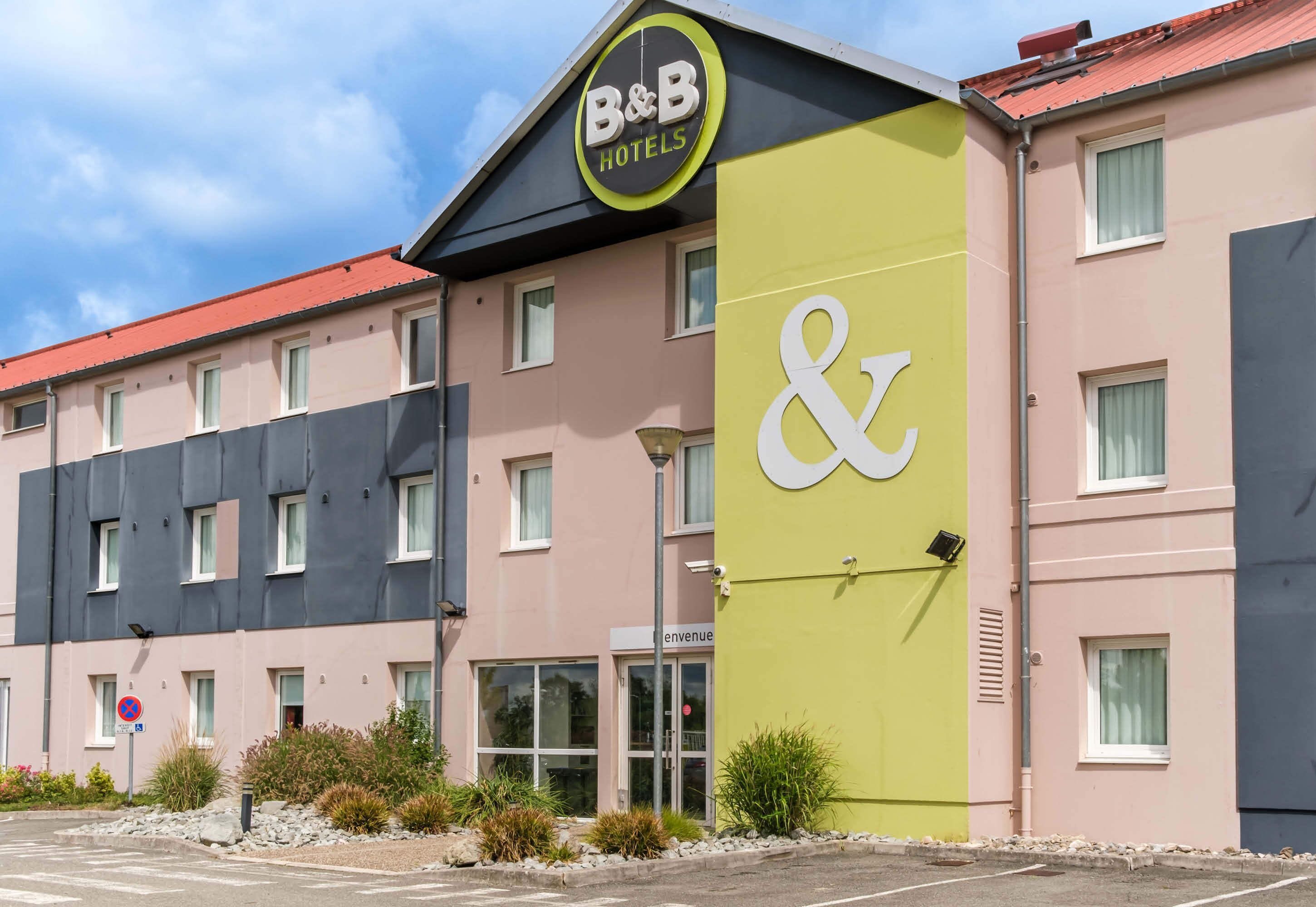 Een bed-en-breakfast hotel met een opvallend bord, een parkeerplaats en een gevel met meerdere ramen.