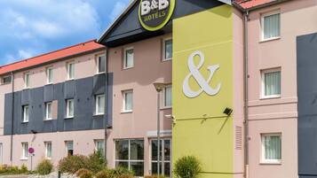 Een bed-en-breakfast hotel met een opvallend bord, een parkeerplaats en een gevel met meerdere ramen.