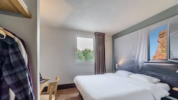 Um quarto com uma cama, uma escrivaninha e uma cadeira.