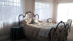 Een slaapkamer met een bed, een stoel en een klein tafeltje.