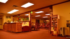 A hotel lobby with a reception desk, multiple chairs, a bookshelf, and a thermostat. - Wells Chinatown (Wells)